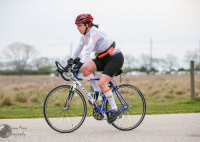 Bike rider in athletic gear cycling outdoors on a cloudy day for fitness and recreation.