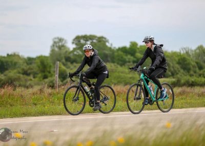 Vibrant women cycling on Bluebonnet Express trail in Texas with lush greenery and open skies.