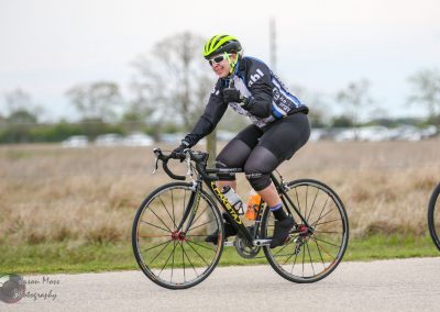 Bright green helmet and sunglasses worn by cyclist riding on a paved trail during daytime.