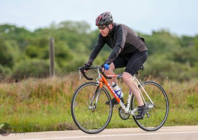 Bright orange and white road bike on scenic outdoor cycling trail in Texas, active cyclist enjoying a ride.