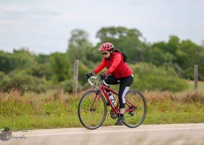 Rider on a Red Bike in Nature, cycling outdoors, Bluebonnet Express bike ride, scenic trail, cycling for fitness and adventure.