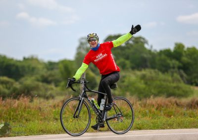 Joyful cyclist celebrating on Bike Trail during Bluebonnet Express event in Texas.