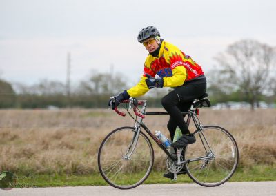 Bright cyclist in colorful jacket on Bluebonnet Express bike ride, giving thumbs-up outdoors.