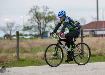 High-performance cyclist riding a Specialized bike on a rural trail with a blue helmet.