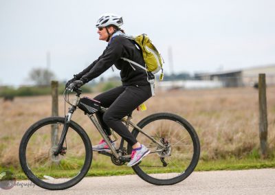 Female cyclist riding electric mountain bike on scenic trail, promoting Bluebonnet Express bike tours.