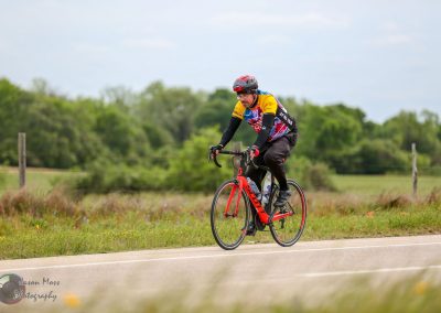 Vibrant cyclist riding a red bike on scenic outdoor trail during daytime.