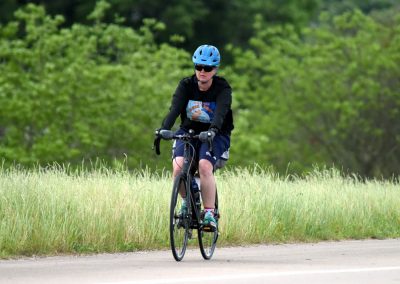 Bluebonnet Express cyclist riding through lush green scenery on a biking trail.