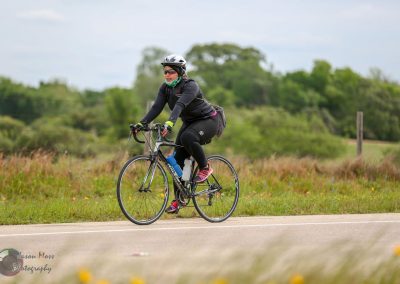 Vegan cyclist riding on a scenic bike trail with lush greenery in the background.