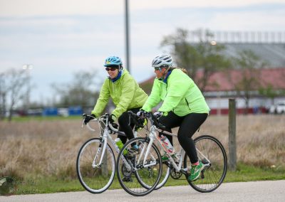 Cyclists riding together in bright colors on a scenic outdoor trail during daytime.