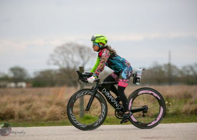 Colorful female cyclist riding a black Diamond bike outdoors with hybrid wheels.