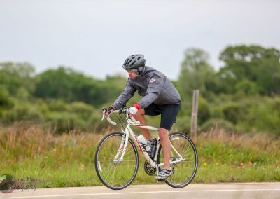 Vegan cyclist riding on scenic rural road with lush greenery.