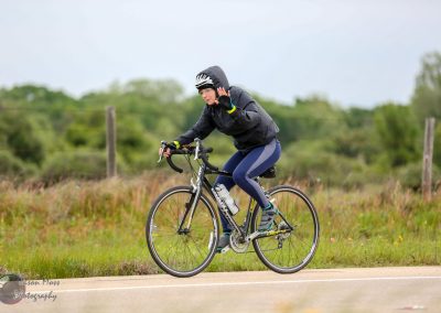 Friendly cyclist riding a bike outdoors with helmet and rain jacket, scenic nature background.
