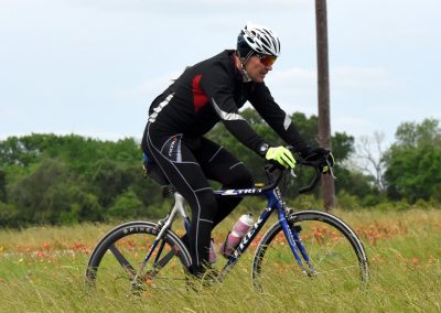 Velo cyclist riding through a grassy field with wildflowers, showcasing outdoor biking adventure.