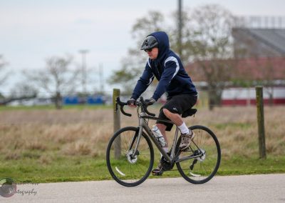 Comfortable outdoor cycling on a modern bike, wearing helmet, hoodie, shorts; scenic park background.