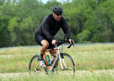 Man biking outdoors on a scenic trail with lush green trees in the background.