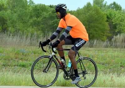 Vegan cyclist riding mountain bike through lush green landscape for Bluebonnet Express event.