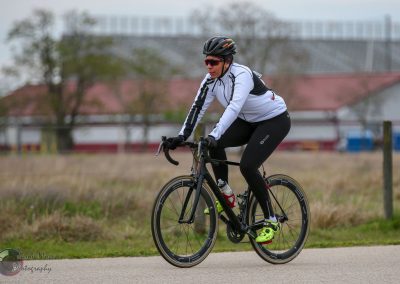 High-performance cyclist riding Bluebonnet Express bike on open road in athletic gear.