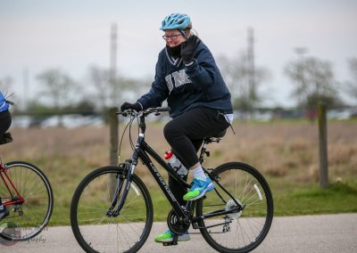 Bright blue helmet and athletic clothing on woman riding Bluebonnet Express bike outdoors.