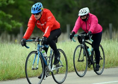 Cyclists riding on a scenic outdoor trail, promoting Bluebonnet Express cycling event.