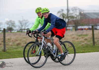 Active cyclists riding bicycles on a paved trail, enjoying outdoor recreation and fitness.