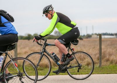 Active cyclist riding a bike in outdoor race or group ride during daytime, emphasizing fitness and adventure.