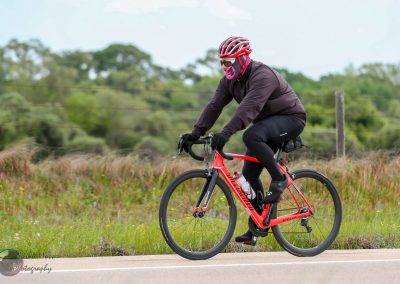 Bright red Specialized bicycle rider on Bluebonnet Express road cycling route.