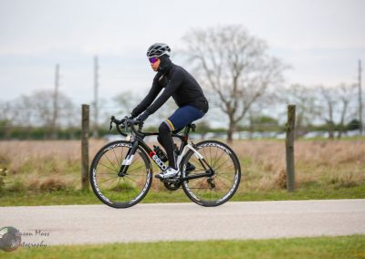 Bright bluebonnet-themed cycling jersey on cyclist riding a racing bike outdoors.