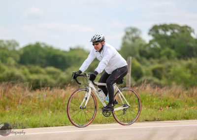 High-quality image of man riding a road bicycle outdoors in nature, wearing sports gear and helmet.