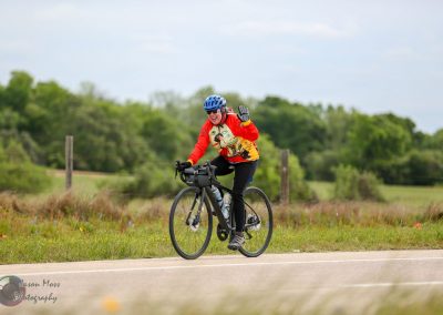 Vibrant cyclist enjoying a ride along a scenic rural route with lush greenery and blue skies.