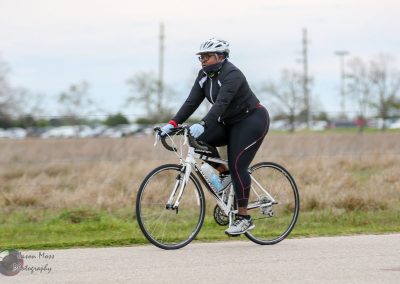 Comfortable woman riding a bike on the Bluebonnet Express trail during daytime.