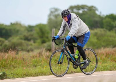 Stormy weather cyclist riding mountain bike on country road, wearing rain gear and helmet.