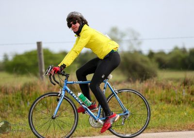 Bright yellow cycling jacket on male cyclist riding a Bluebonnet Express bike outdoors.