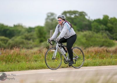 Cyclist riding a bike on a scenic trail with lush greenery in the background.
