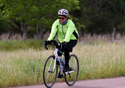 Vegan Bicycle rider in neon green jacket on scenic countryside bike trail.