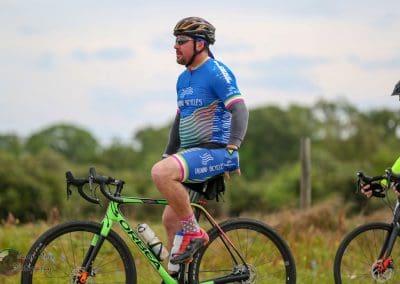 Men in colorful cycling jerseys riding bikes outdoors on scenic trail.