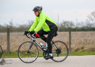 Vibrant yellow and black cycling jacket on man riding a Giant road bike outdoors during daytime.