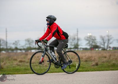 Smooth-riding cyclist wearing red jacket and helmet on Bluebonnet Express trail.