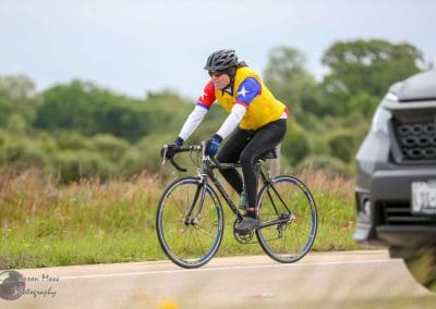 Bike touring on scenic highway with a cyclist wearing a colorful jersey and helmet.