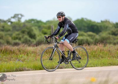 Vast cycling scene featuring a man riding a road bike on a scenic outdoor path.