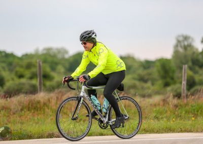 Bright neon yellow cycling jacket riding a Cannondale road bike through a rural landscape, illustrating athletic outdoor biking.