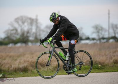 High-performance cyclist riding a road bike in outdoor setting with a branded Green and black bicycle.