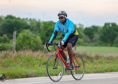 Vibrant cyclist riding on scenic outdoor trail with lush greenery and blue sky.