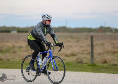 Smooth road cyclist riding a Bluebonnet Express bike on rural trail.