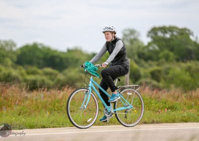 Cyclist riding along scenic outdoor trail with lush greenery, promoting Green Energy Bike Tours.