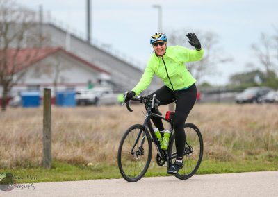 Bright neon green cycling jacket and gear at Bluebonnet Express event, smiling rider waving during bike ride.