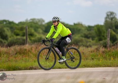Bright yellow cycling jacket at Bluebonnet Express bike race, female cyclist riding through scenic countryside.