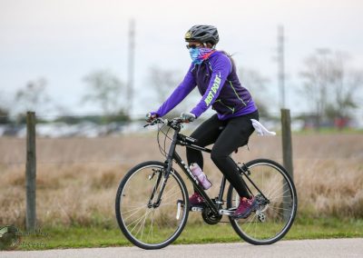Bright purple and black outdoor bike riding jacket on woman cycling in open park.