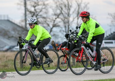 Vibrant cyclists in neon gear riding on a paved trail during daytime.