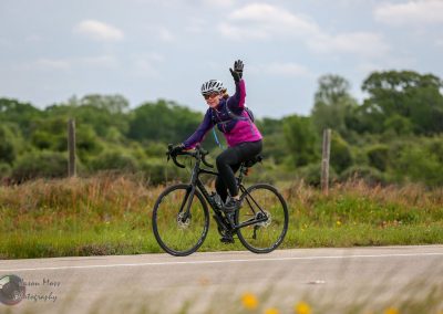 Vibrant cyclist riding a bike on scenic trail, promoting Bluebonnet Express bike tours.
