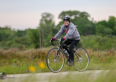 Happy woman cycling outdoors on a Specialized bike, promoting Bluebonnet Express themed bike tours.